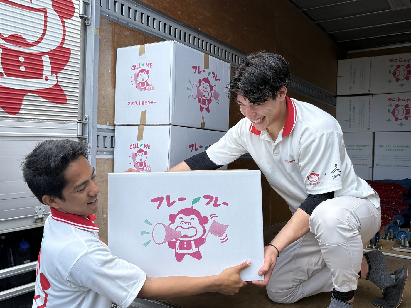 引越トラックの荷台で荷物を受け渡す外国籍スタッフと日本人スタッフ