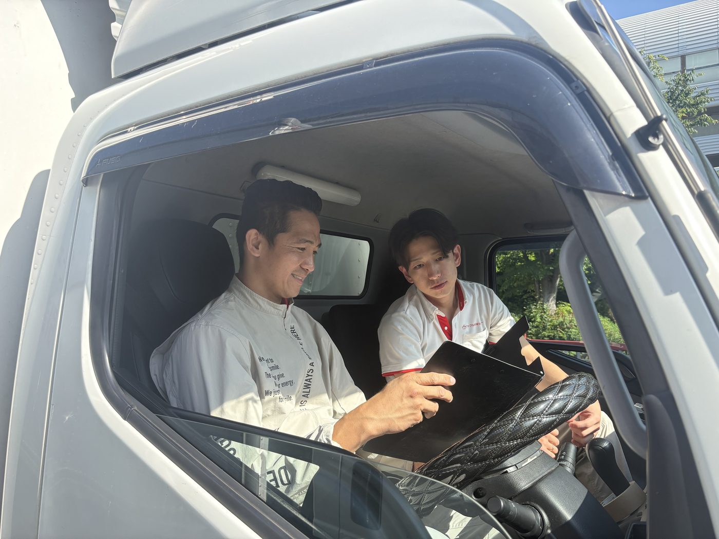 トラックの運転席でロードマップを確認しながら指導を受けるドライバー